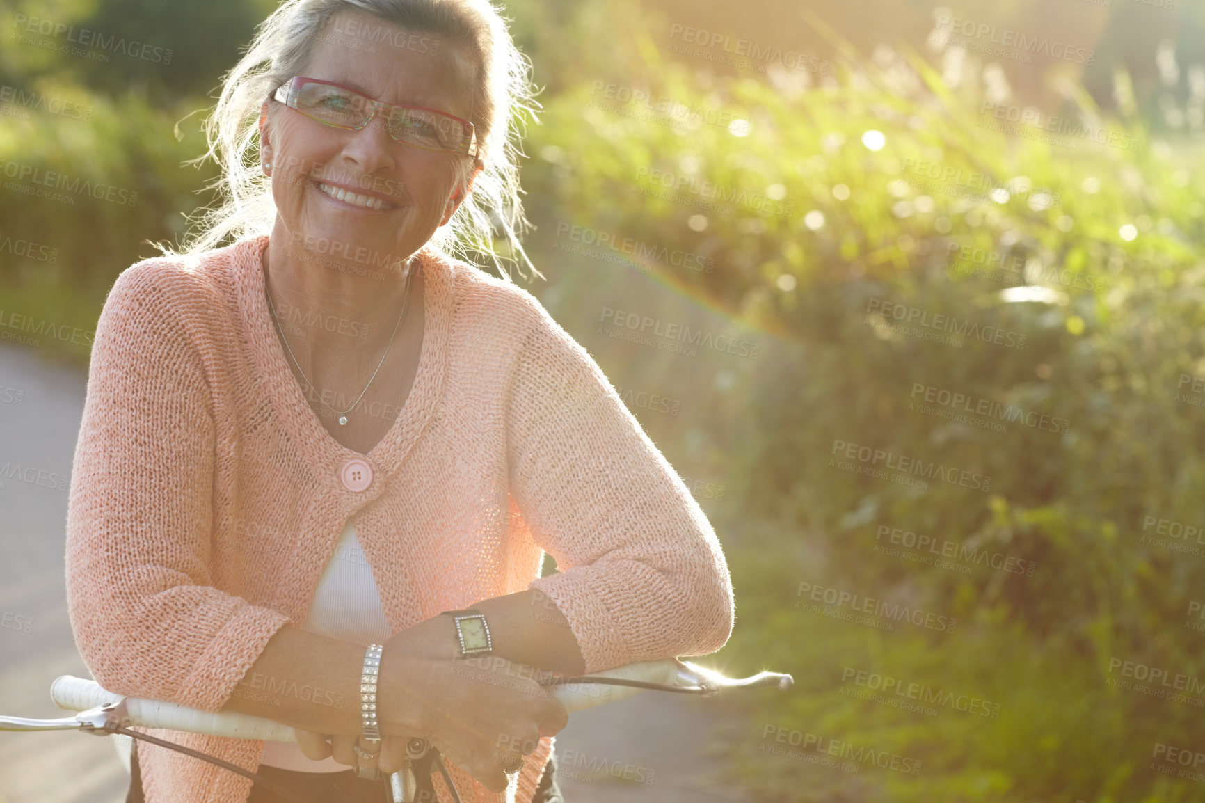 Buy stock photo Portrait, senior and happy woman on bicycle in nature for exercise, wellness and health outdoor. Face, smile and elderly person on bike, glasses at park and cycling in garden or summer countryside