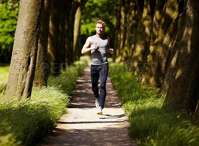 Buy stock photo Young guy out for a jog along a woody path