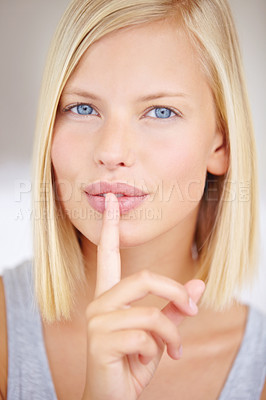Buy stock photo Portrait of a young woman holding her finger in front of her lips