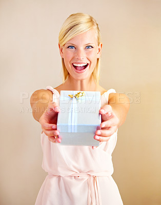 Buy stock photo Portrait of a young woman holding out a gift box and smiling