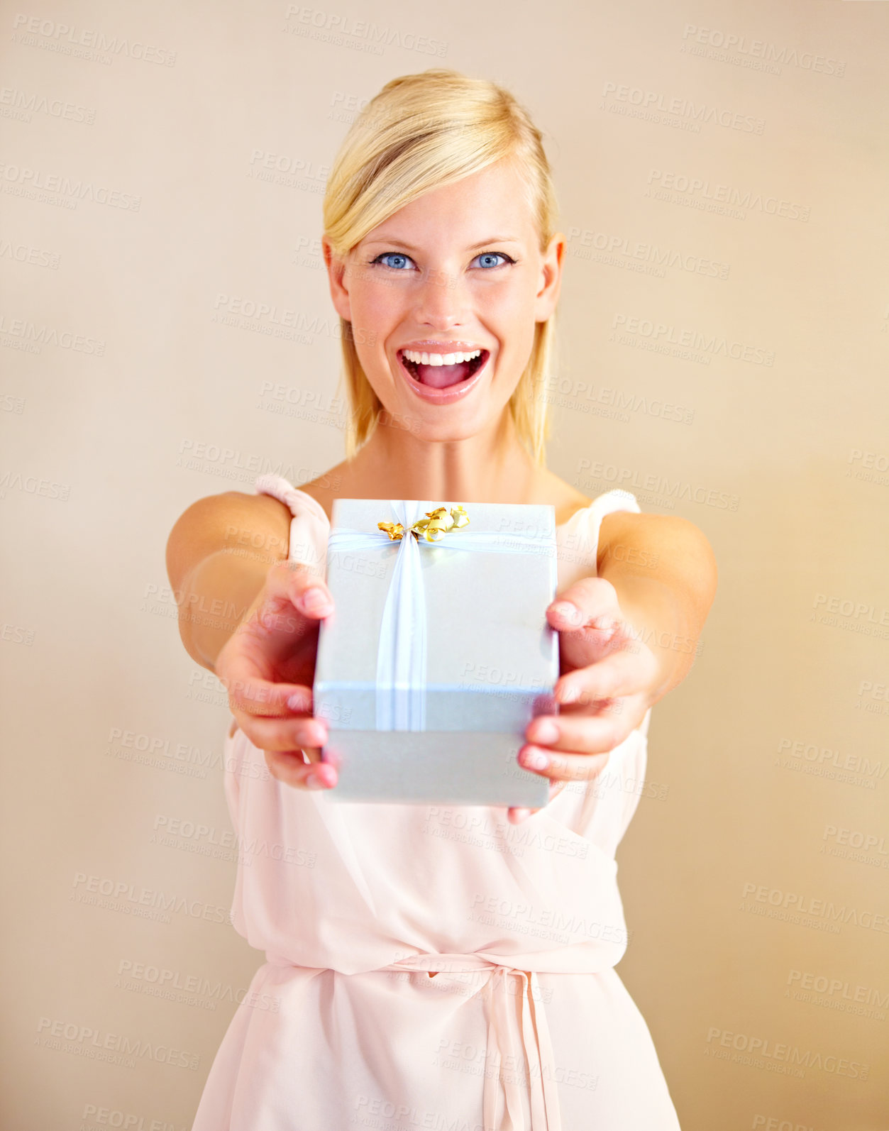 Buy stock photo Portrait of a young woman holding out a gift box and smiling