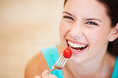 Buy stock photo Portrait of a beautiful young woman eating a baby tomato