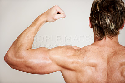 Buy stock photo Back, arm and a man flexing his bicep in studio isolated on a gray background for health, fitness or wellness. Exercise, training and strong with the body of a shirtless model from behind for power