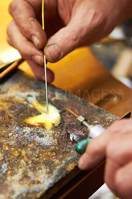 Buy stock photo Cropped view of a manufacturing jeweler heating up solder and using a soldering pick