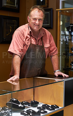 Buy stock photo Smiling jeweler standing behind the display case in his store