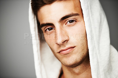 Buy stock photo Serious, portrait and man in hoodie for fashion isolated on a gray background. Confident young person, face of model and streetwear clothes, casual and cool facial expression in Spain on a backdrop