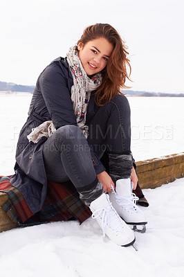 Buy stock photo Pretty teenage girl puttin on her ice skates on a natural frozen lake outdoors