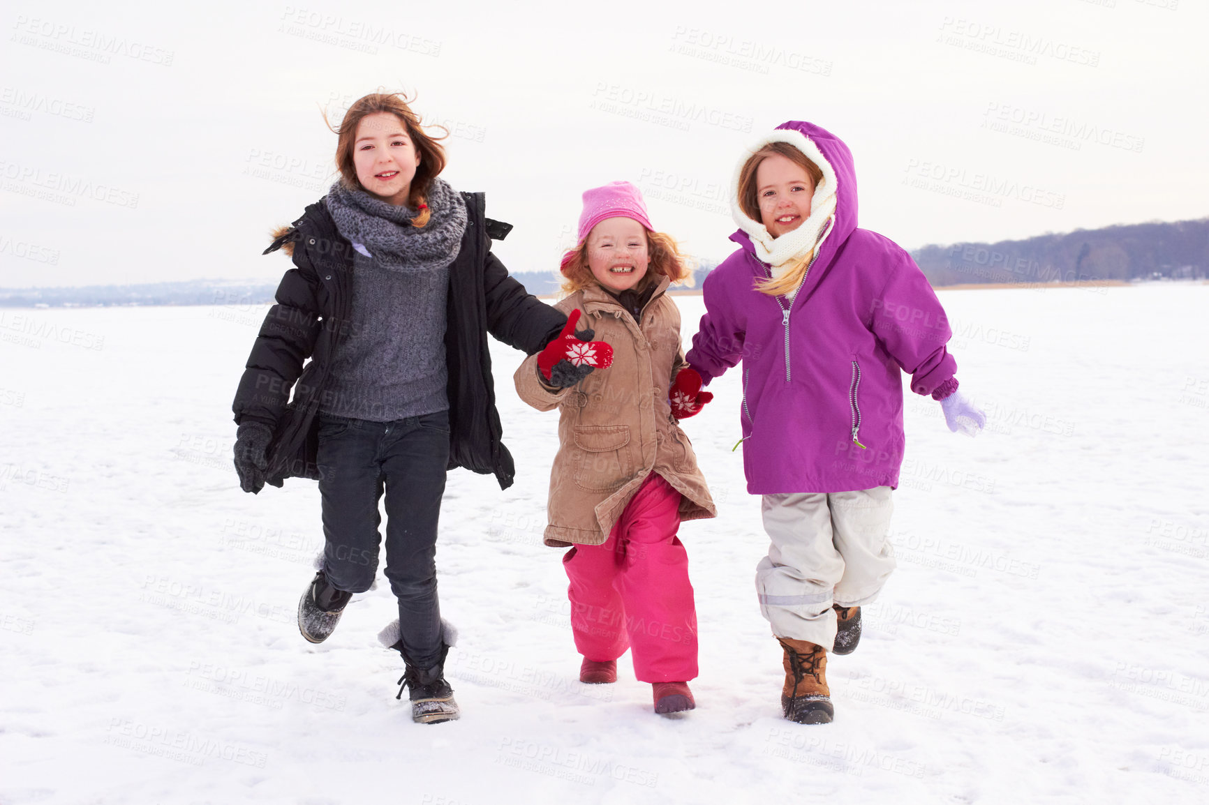Buy stock photo Three young sisters running outside in the snow