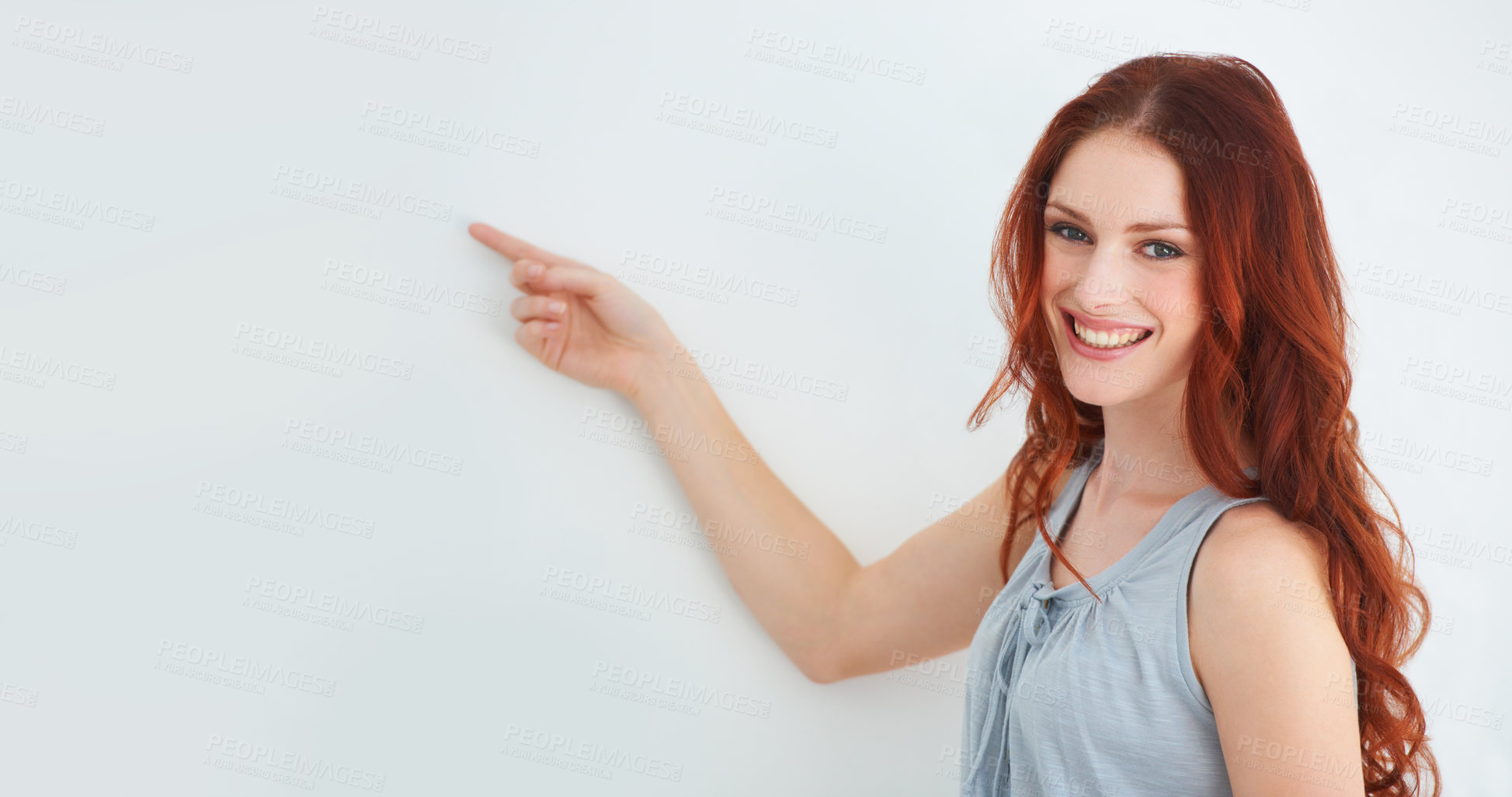 Buy stock photo A young woman pointing at copyspace