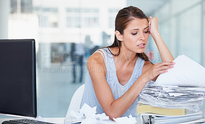 Buy stock photo Shot of a stressed out young businesswoman going through a stack of paperwork