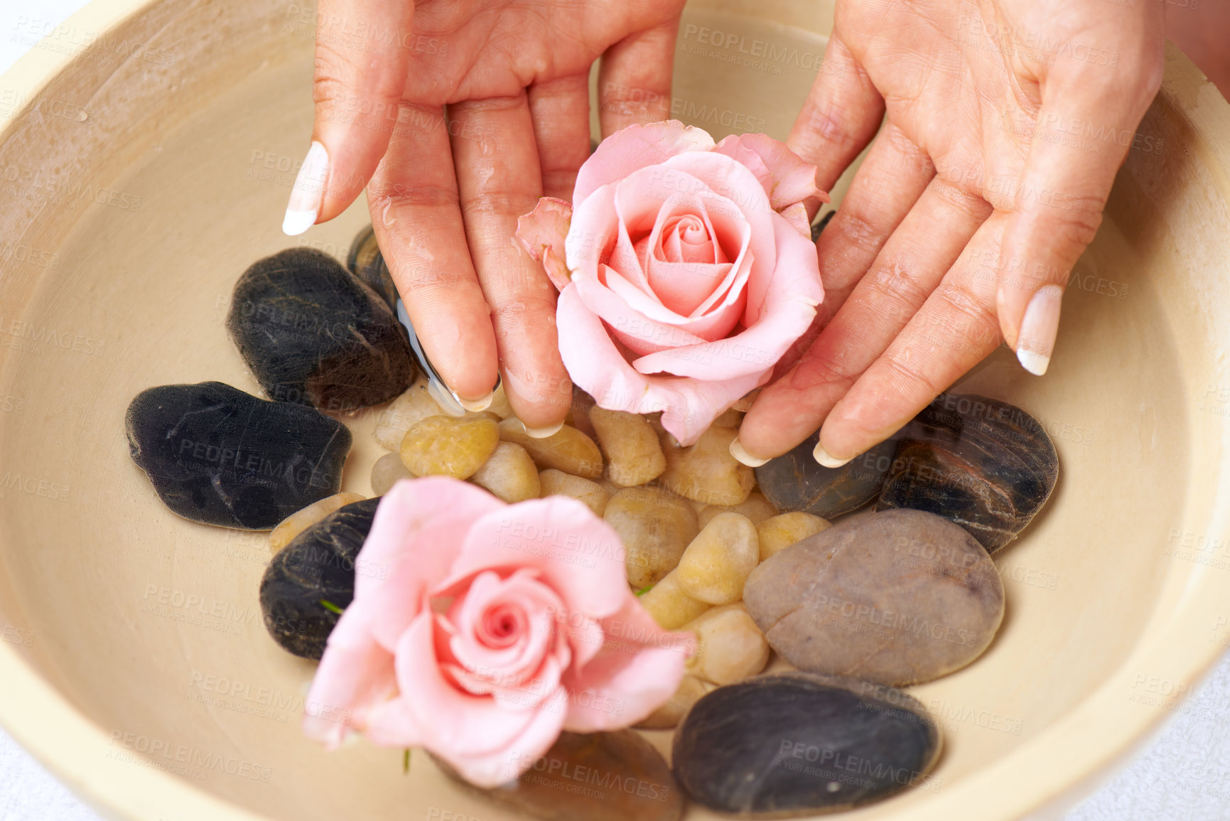 Buy stock photo Flowers, skincare and hands of woman in water bowl for cleaning or hygiene. Floral therapy, spa treatment and female soak hand and washing with pink roses and stones for detox, beauty and manicure.