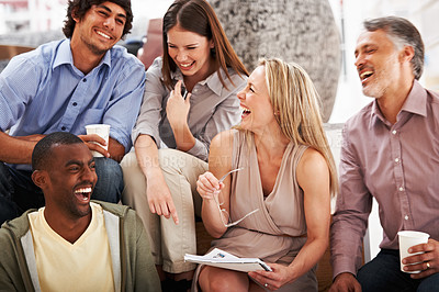 Buy stock photo A team of designers laughing while looking at some ideas