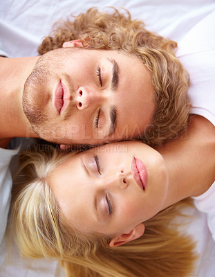 Buy stock photo A young couple sleeping in bed with their heads together