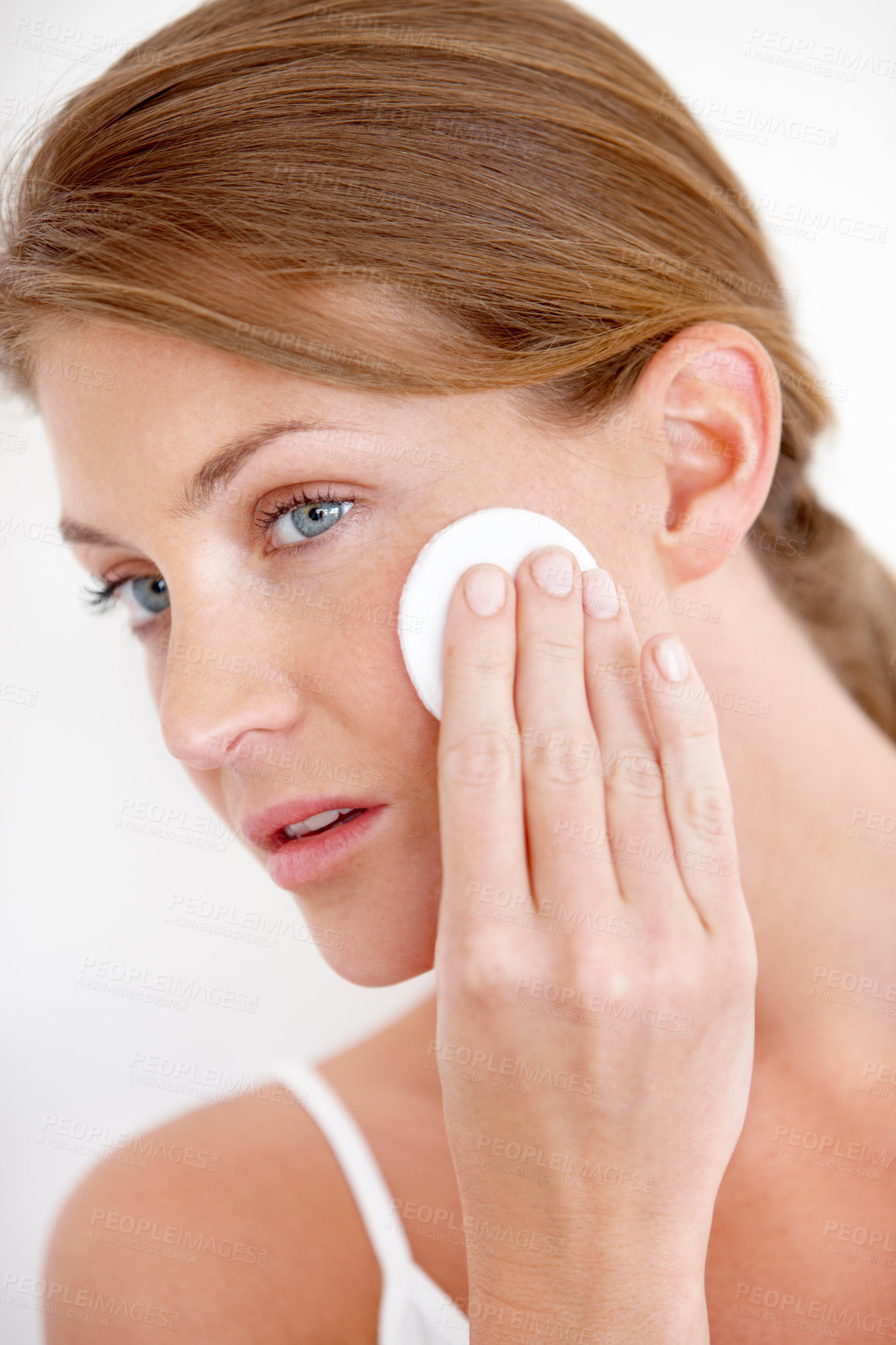 Buy stock photo A lovely young woman applying makeup to her cheek with a cotton pad