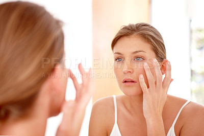 Buy stock photo A naturally gorgeous woman applying moisturizing cream in a mirror