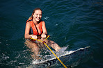 A pretty young woman in the water with a wakeboard wearing a lifejacket