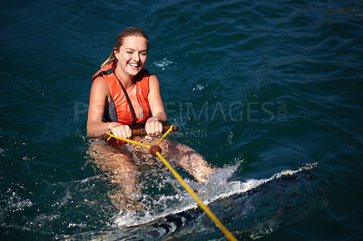Buy stock photo A pretty young woman in the water with a wakeboard wearing a lifejacket