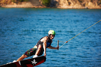 Buy stock photo Man, wakeboarding outdoor and lake with helmet, sport and fitness for speed in summer sunshine. Person, athlete and ski with rope for safety on water, sea or river for training, exercise and freedom