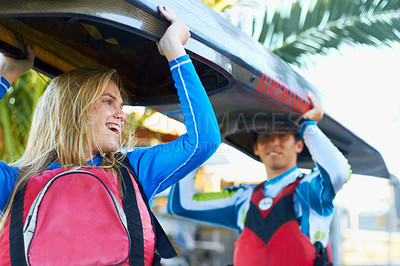 Buy stock photo A cropped shot of two young people carrying a kayak