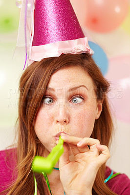Buy stock photo Portrait of an attractive young woman pulling a silly face while blowing a party blower 
