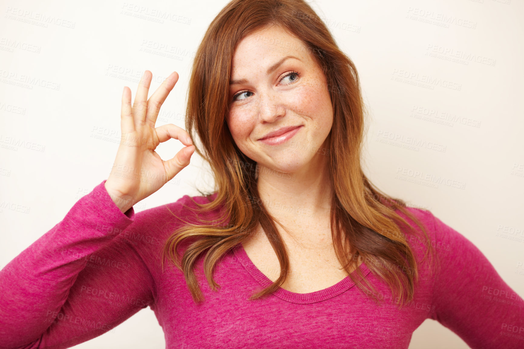 Buy stock photo Cropped shot of a beautiful young woman smiling while showing an ok sign