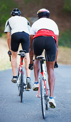 Buy stock photo Rearview shot of two riders cycling down a rural road together