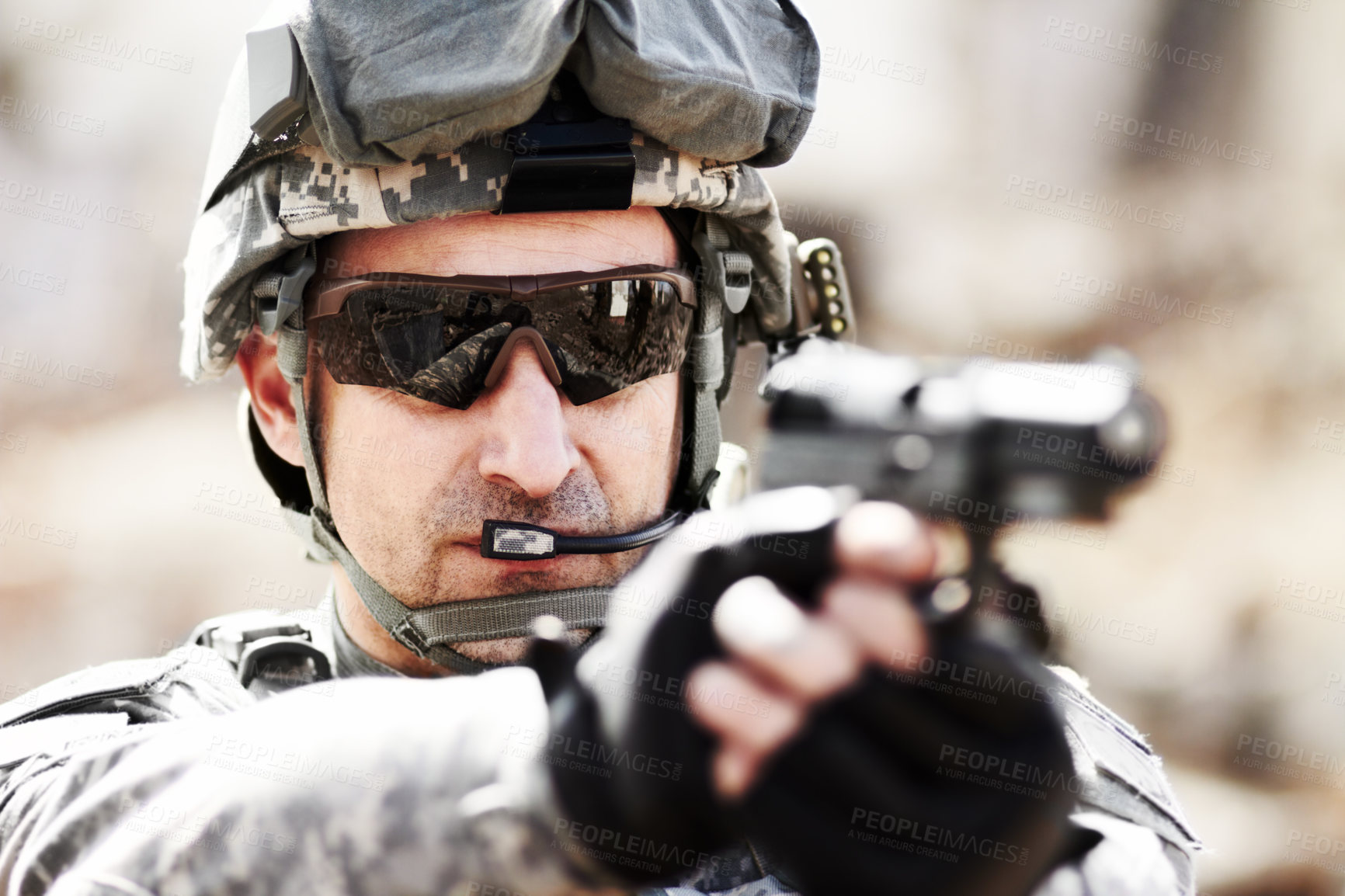 Buy stock photo Closeup head and shoulders shot of a soldier pointing his hand gun