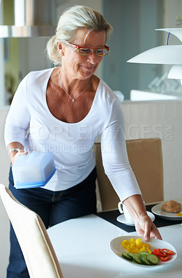 Buy stock photo Senior, woman and table prepare for breakfast meal or hosting healthy on holiday vacation, happy in kitchen event. Female person, smile and plate or vegetables food, organic fresh or hungry nutrition