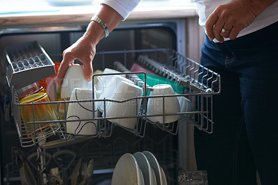 Buy stock photo A senior woman putting her dishes into a dishwasher