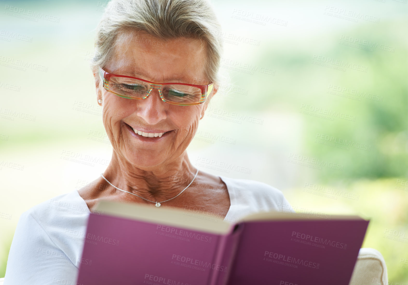 Buy stock photo A delighted woman reading an enjoyable book in her lounge