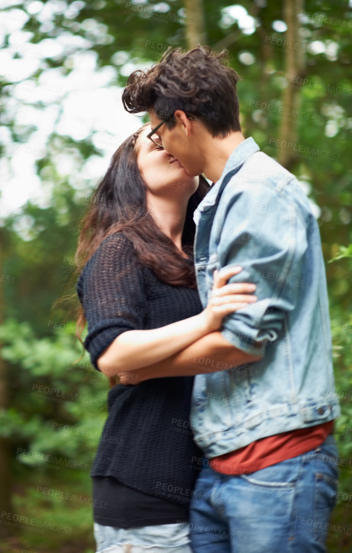 Buy stock photo Cute young couple standing outside and kissing