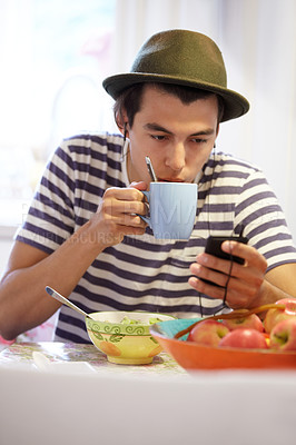 Buy stock photo Young guy texting while drinking his coffee at home