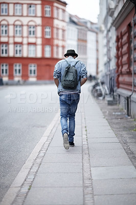 Buy stock photo Rear view of a young guy walking down a city street