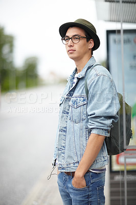 Buy stock photo Hip young guy standing  at a bus stop with his hands in his pockets