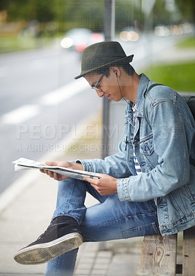 Buy stock photo Man, commute and bus stop with newspaper, travel and adventure on journey, transportation and reading for trip. Male person, earphones and headlines or music, smile and happy for article in outdoors