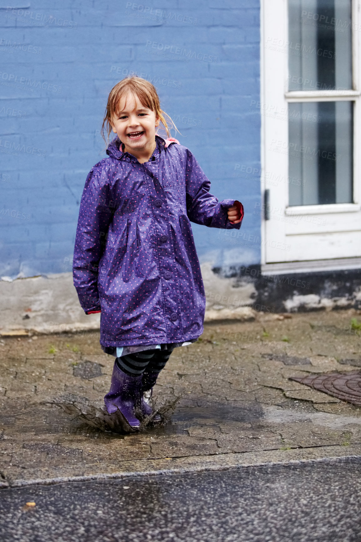Buy stock photo Child, portrait and splash in mud puddle in raincoat for winter fun, explore city or cold weather happy. Young girl, excited and water on holiday vacation break for wet game or joy, surprise as kid