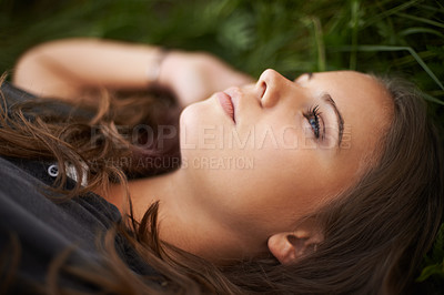Buy stock photo Face, thinking and relax with a woman on grass outdoor in a field closeup for daydreaming in summer. Peace, freedom and mind with a young person lying in a park for mental health, zen or awareness