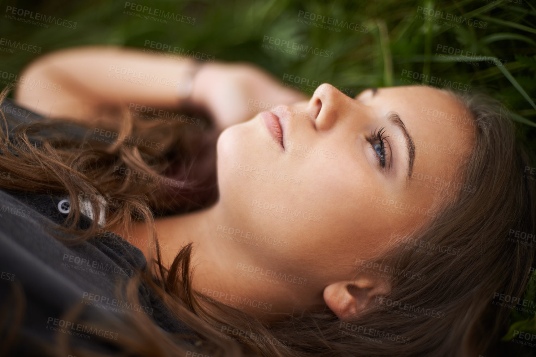 Buy stock photo Face, thinking and relax with a woman on grass outdoor in a field closeup for daydreaming in summer. Peace, freedom and mind with a young person lying in a park for mental health, zen or awareness