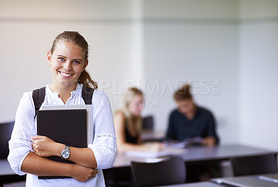Buy stock photo A teenage girl holding her laptop while standing in the classroom