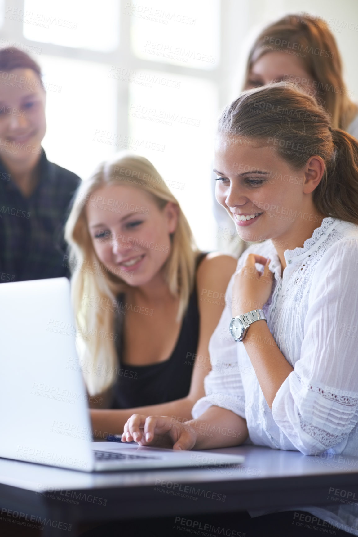 Buy stock photo A group of teenage girls working together on a laptop in the classroom