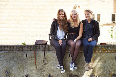 Buy stock photo College, friends and portrait of sitting on a wall, outdoor on campus with women and happiness. Social, students and smile for learning, education and studying at academy with backpack in morning
