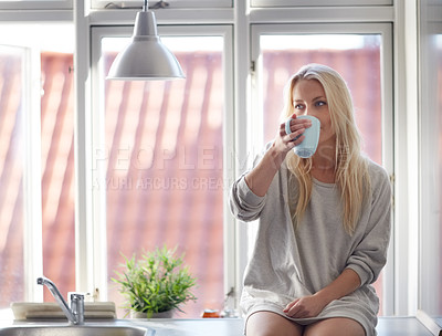 Buy stock photo A pretty young woman enjoying a cup of coffee in the morning while sitting on a window sill