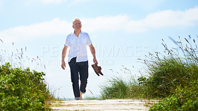 Buy stock photo A senior man walking through a park with his shoes in hand