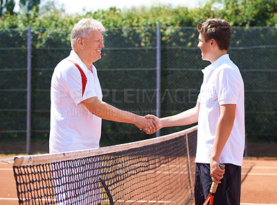 Buy stock photo A father and son shaking hands after a friendly game of tennis