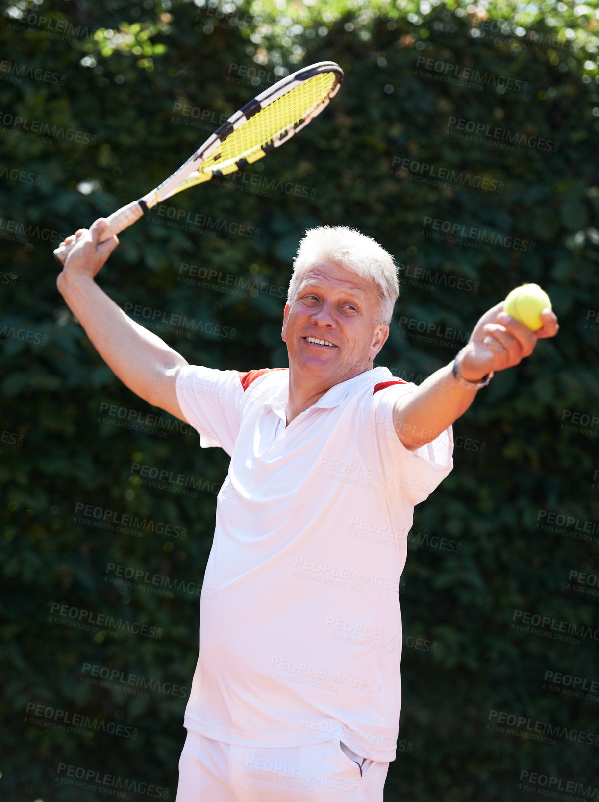 Buy stock photo A senior man serving while playing tennis