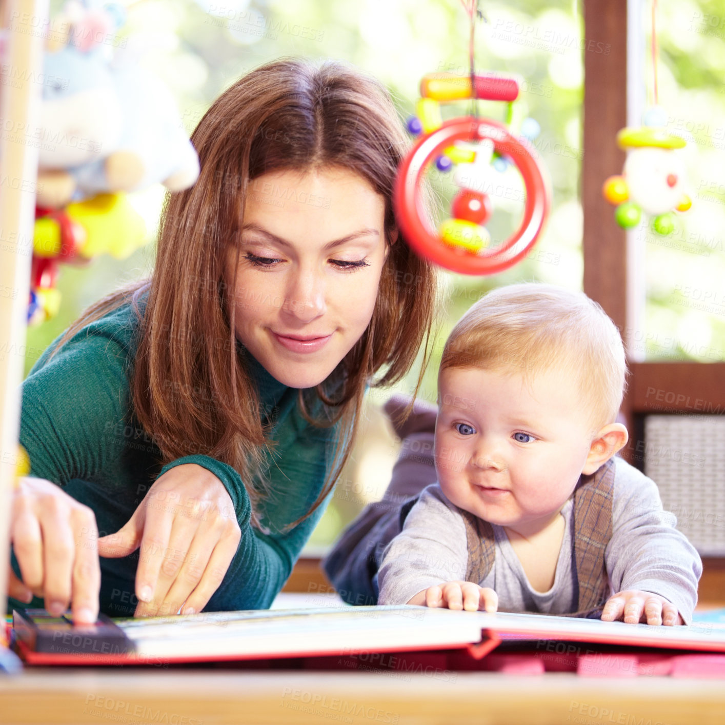 Buy stock photo Cute young mom lying alongside her infant son on the playroom floor