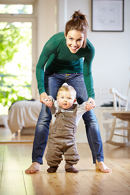 Buy stock photo Smiling young mom helping her baby boy learn to walk