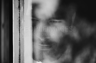 Buy stock photo Closeup of a thoughtful young man seen through a window