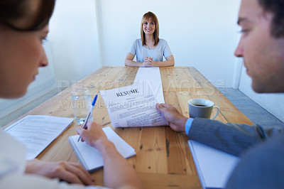 Buy stock photo A pretty young woman sitting at the end of the table as two businesspeople go over her long resume