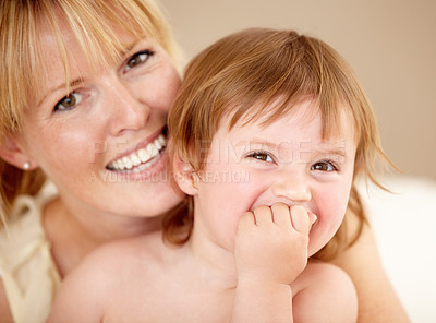 Buy stock photo Smiling mother holding her little girl as she laughs with her hand covering her mouth